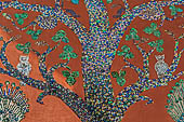 Wat Xieng Thong temple in Luang Prabang, Laos. Detail of the famous tree of life mosaic of the back wall of the sim, in colored glass on a dark red background. 